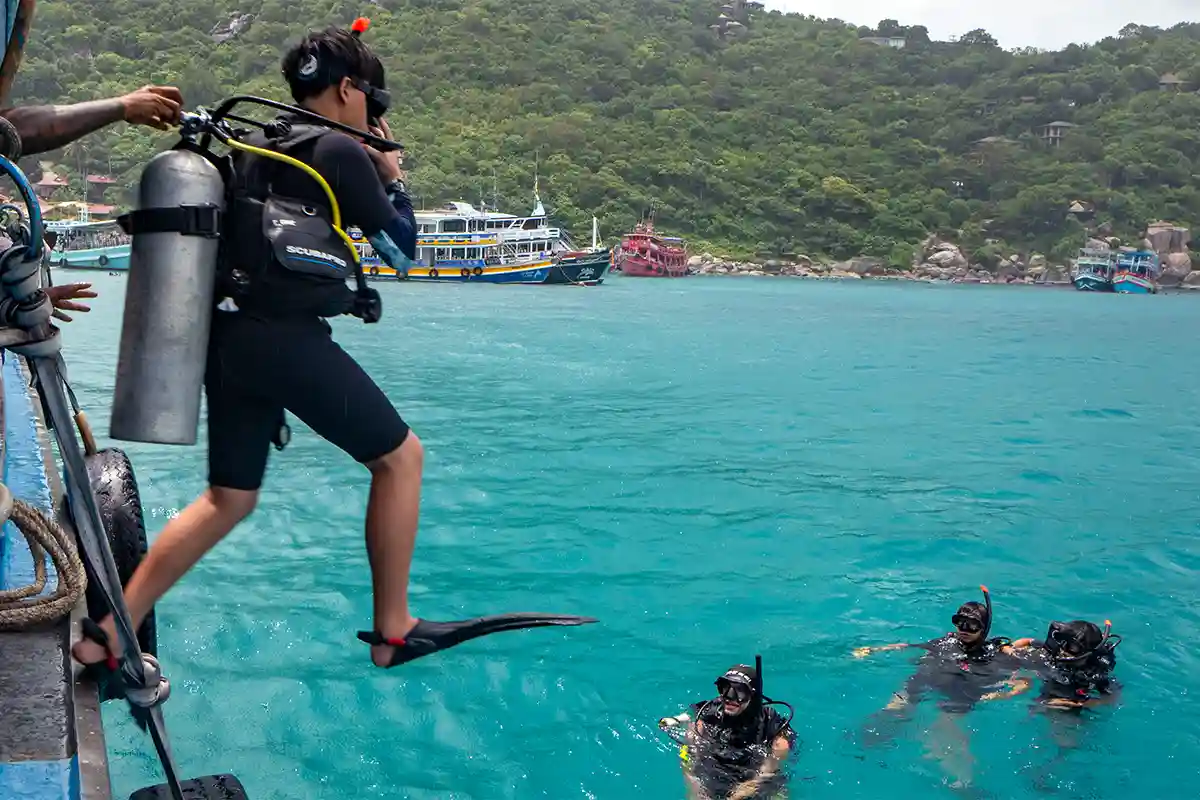 PADI Advanced Open Water Boat Entry in Koh Tao Diver making a giant stride entry from a dive boat while other divers wait in the water in Koh Tao