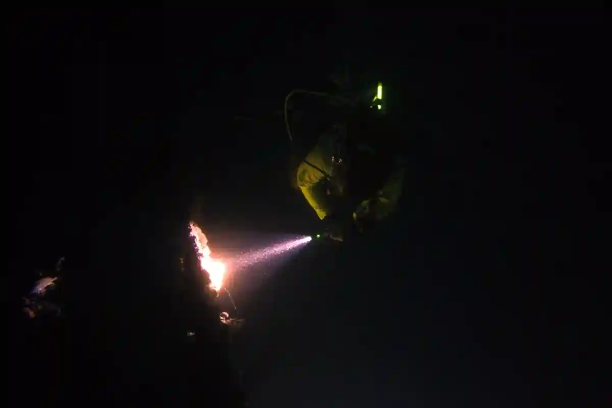 Night Diver Exploring by Torchlight in Koh Tao Scuba diver using a torch during a night dive in Koh Tao