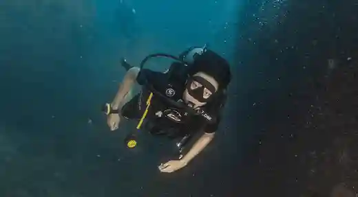 Exploring Koh Tao with Nitrox Scuba diver exploring beside an underwater rock formation in Koh Tao