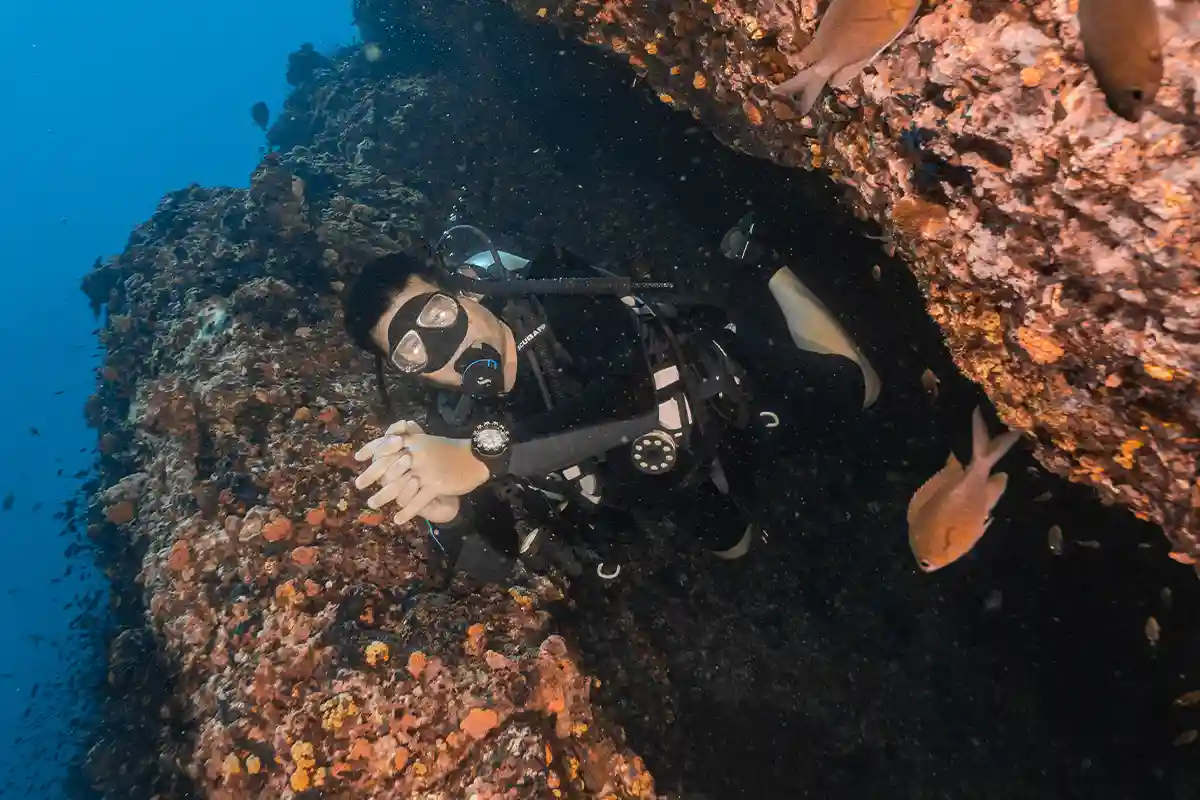 PADI Nitrox Specialty Diver Under Overhang in Koh Tao Diver swimming beneath a rocky overhang in Koh Tao