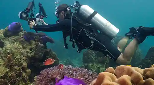 Pro Underwater Photography Course in Koh Tao Underwater photographer using a professional camera system above a coral reef in Koh Tao