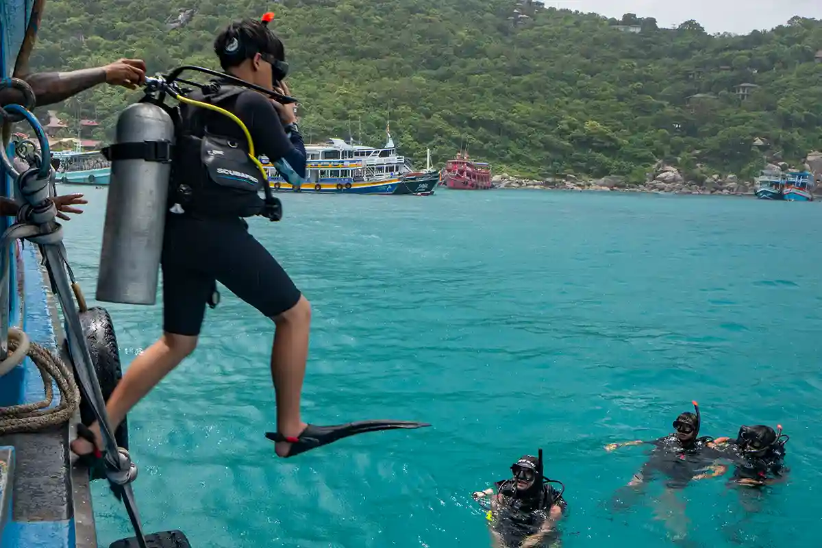 Scuba Refresher Koh Tao | Flow Divers Certified diver entering the water from a dive boat for a scuba refresher in Koh Tao