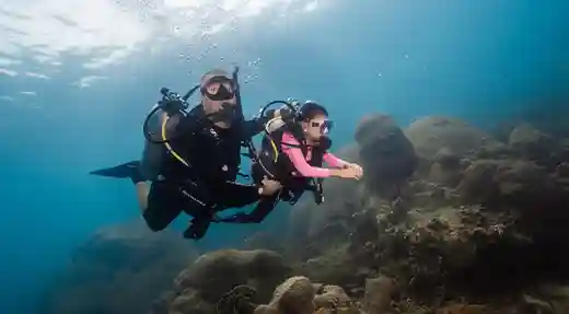 PADI Bubblemaker Coral Dive in Koh Tao Child scuba diving with a PADI Professional beside coral in Koh Tao.