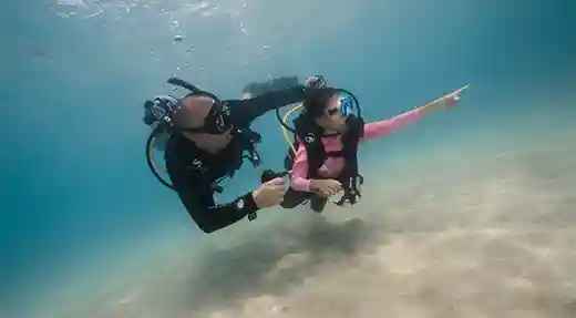 PADI Bubblemaker Shallow Ocean Dive in Koh Tao Child scuba diving in shallow water with a PADI Professional during a Bubblemaker Experience in Koh Tao.