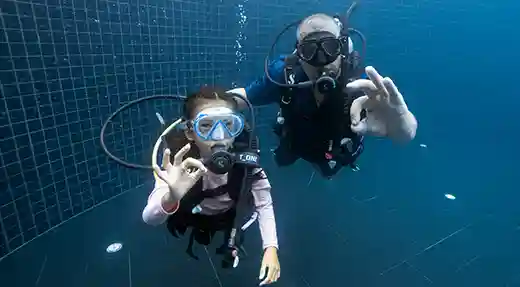 PADI Bubblemaker Underwater Pool Session Child and PADI Professional practising underwater during a Bubblemaker pool session in Koh Tao.